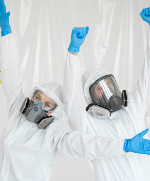 Portraits of a doctor: a man and a woman in protective suits and respirators, wearing gloves, having fun during quarantine. Covid-19.